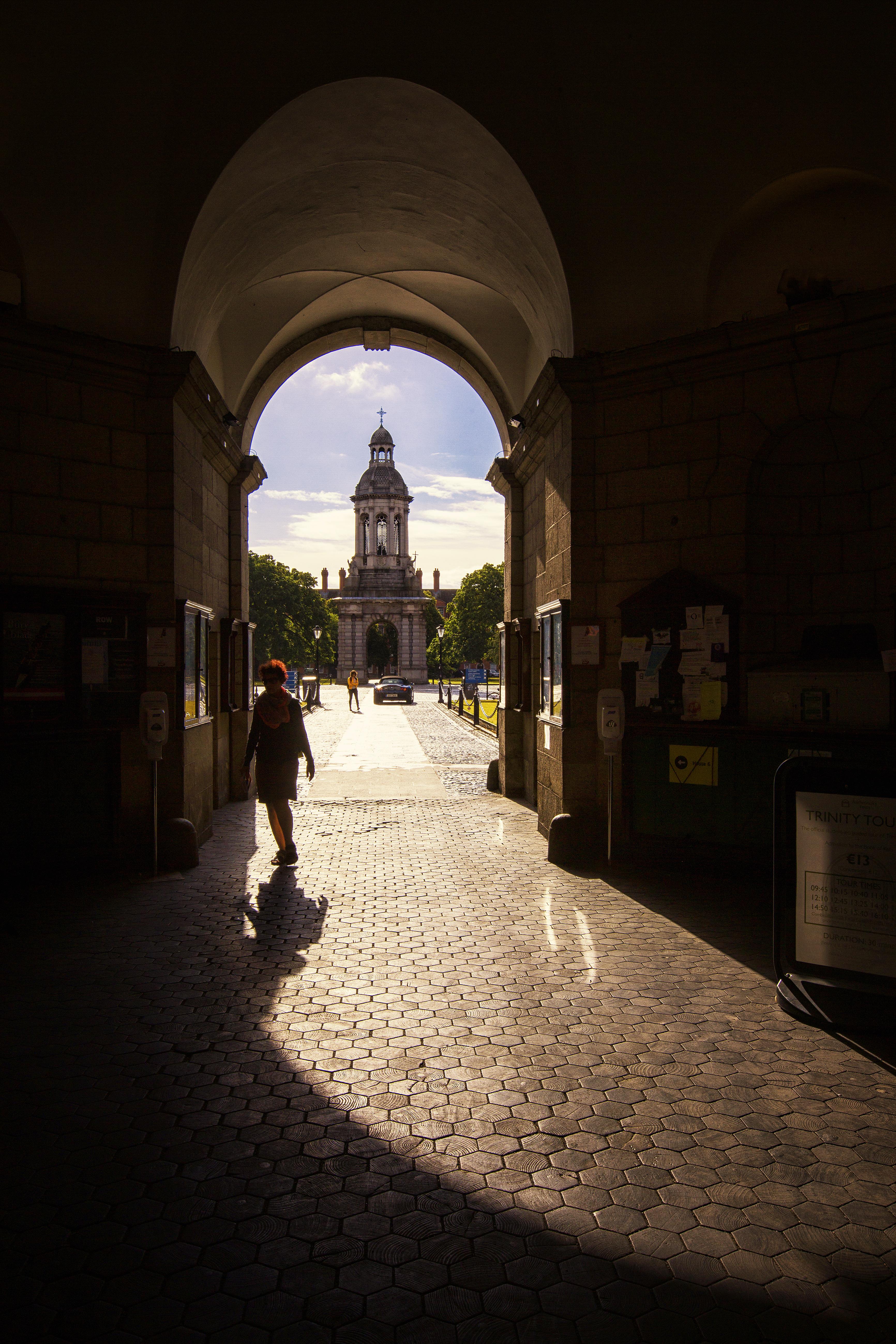 Person silhouetted in archway against the sun.